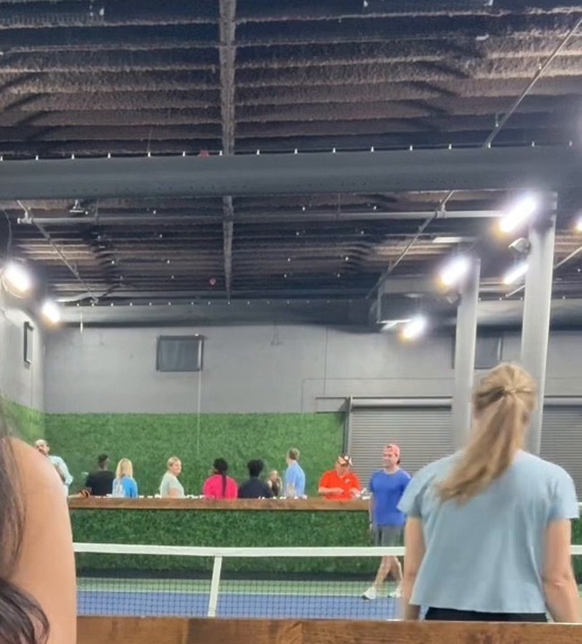 Wide live venue context showing the court, people and working room.
