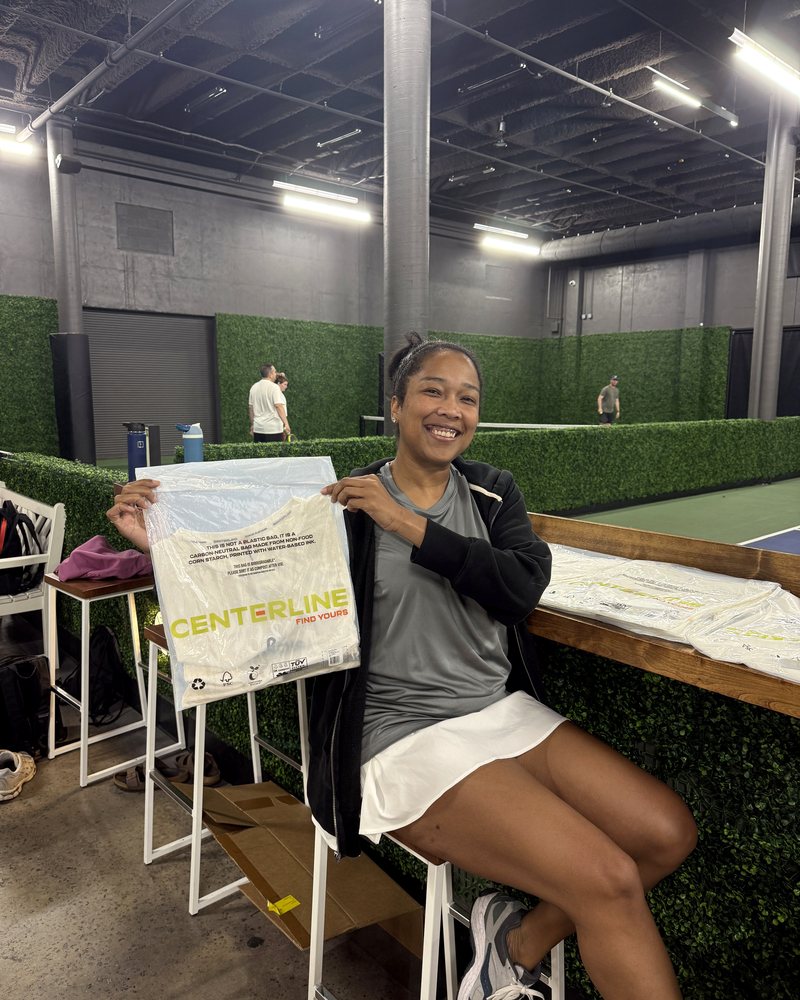 Lauren Bush courtside holding up a Centerline apparel package at a Honcho pickleball venue.