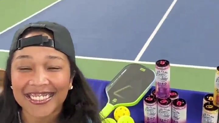 Lauren Bush hosting with a handheld microphone at a live pickleball venue.
